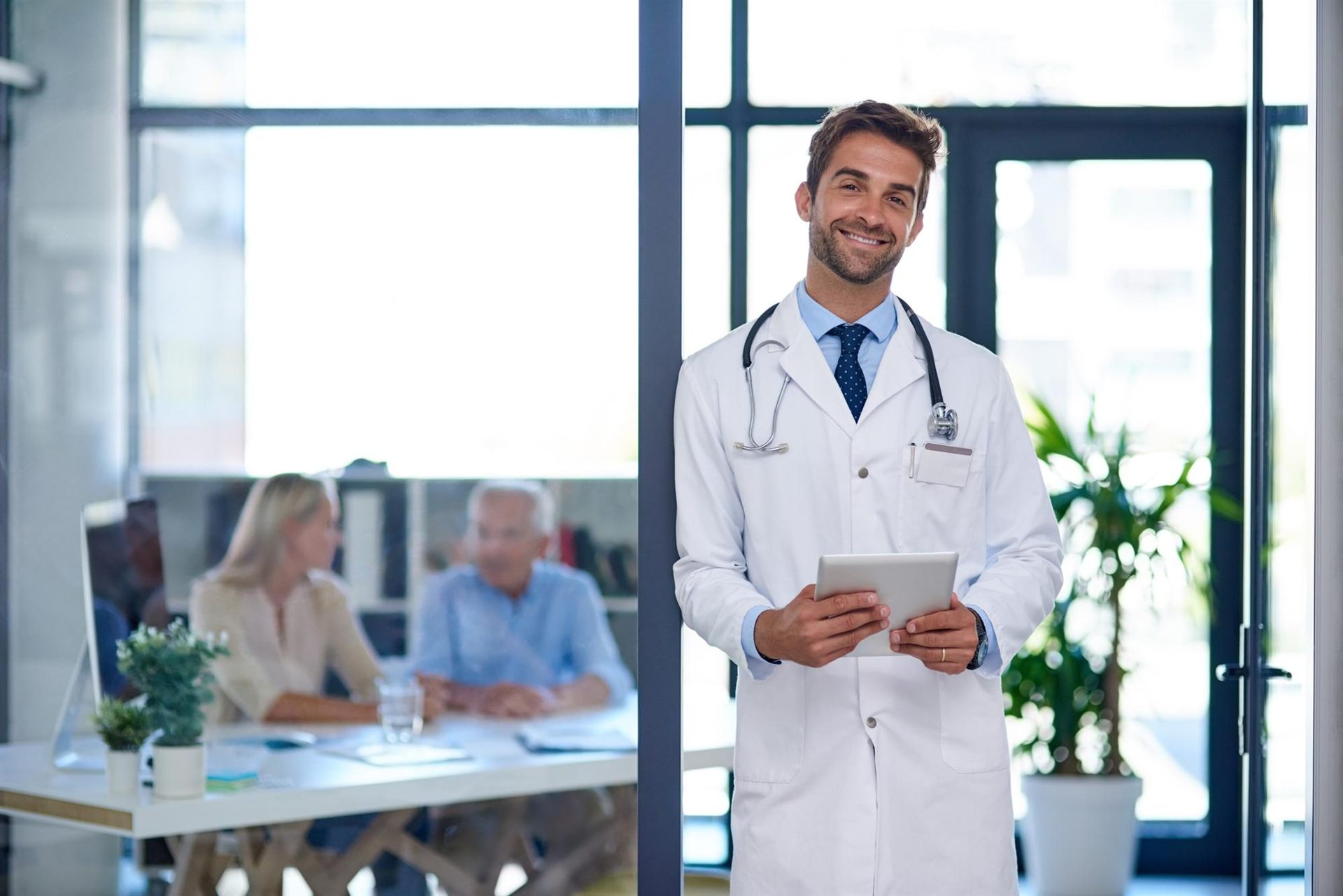 Médico prescritor com jaleco e tablet em consultório